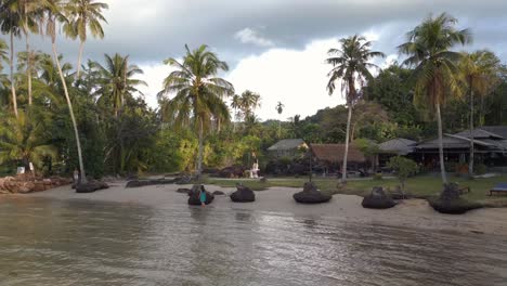 Hammock-on-beach-woman-walking-through-water