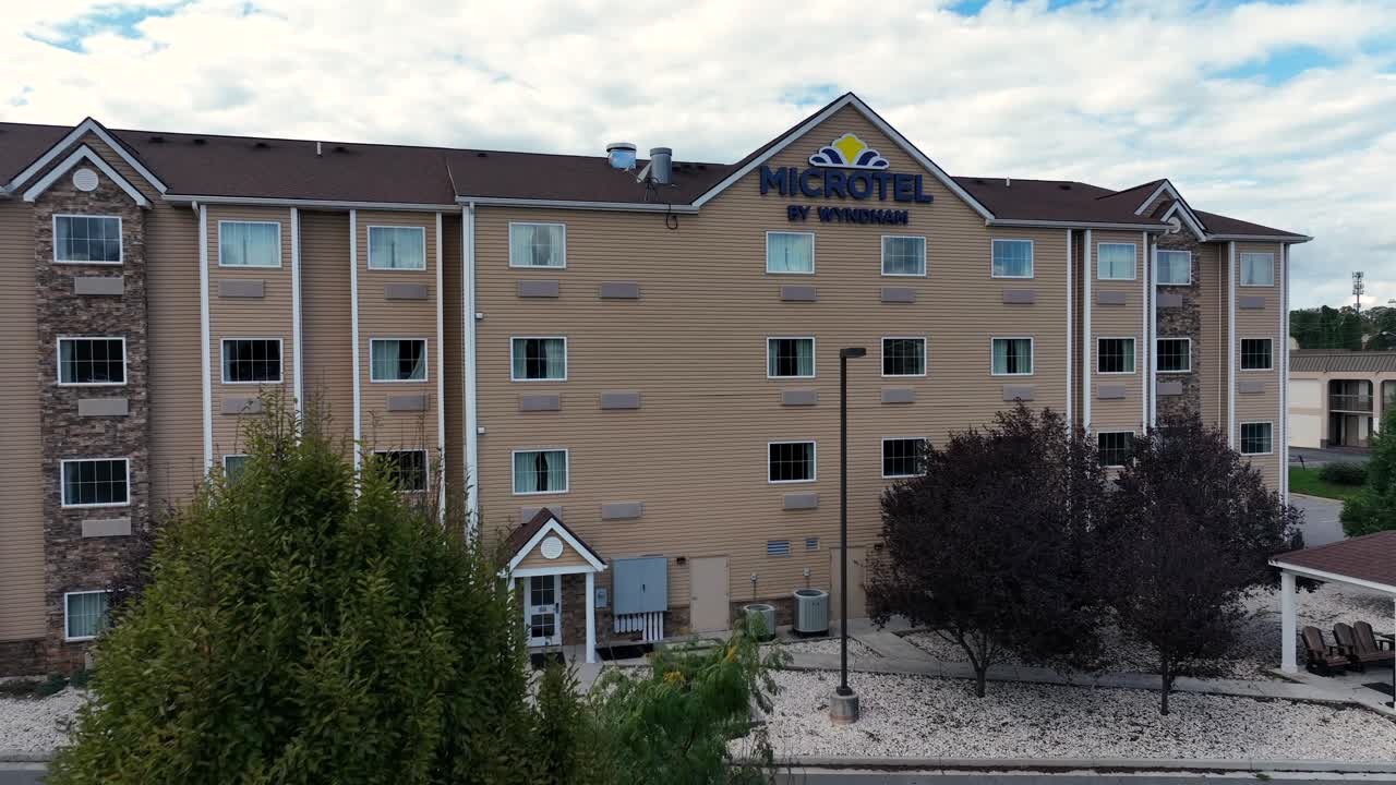 Aerial approaching shot of Microtel by Wyndham in american town during cloudy summer day. Large Hotel block for tourist and people.