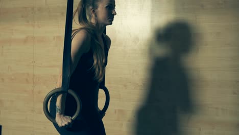 woman doing pull-ups in a gym on gymnastic rings