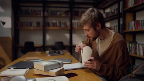 student eating noodle lunch in library