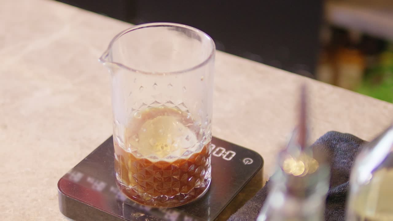 A bartender skillfully measures and mixes ingredients to create a unique cocktail.