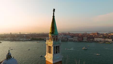 bell tower with dark angel statue at san giorgio maggiore in venice, italy during sunset