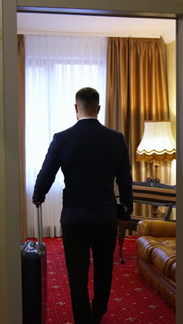 handsome man walking in a hotel room after business meeting. businessman enters apartment in luxury hotel. vertical video