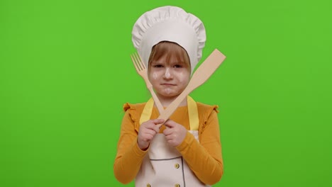 niña niño vestido como cocinero chef con tenedor y espátula, mostrando símbolo de rechazo, desacuerdo