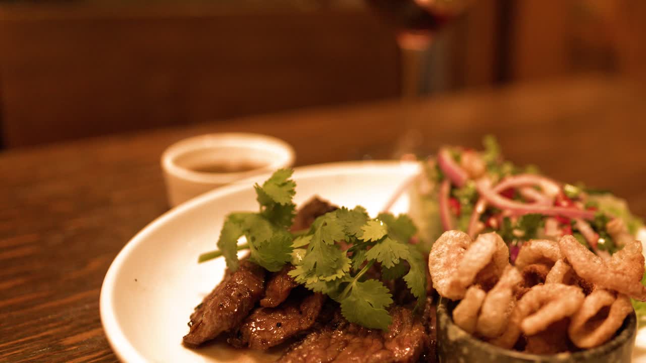 Close-up shot of gourmet Thai fusion steak and crispy pork served with red wine