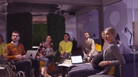 muslim woman in a modern open space coworking office giving a presentation to team. middle eastern arab businesswoman in creative startup office. disabled businessman in a wheelchair on team meeting