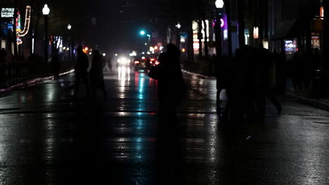 night reflections on a wet city street with pedestrians