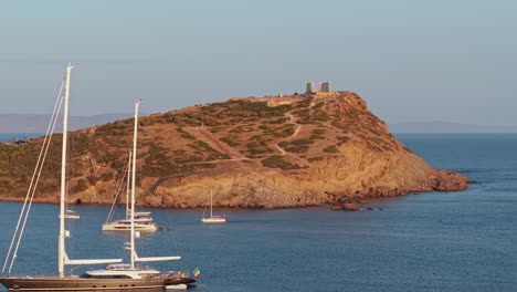 revealing a luxury sailing boat with the temple of poseidon in the background during sunset, blending ancient heritage with maritime elegance