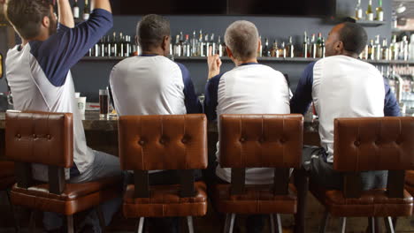 rear view of male friends watching game in sports bar