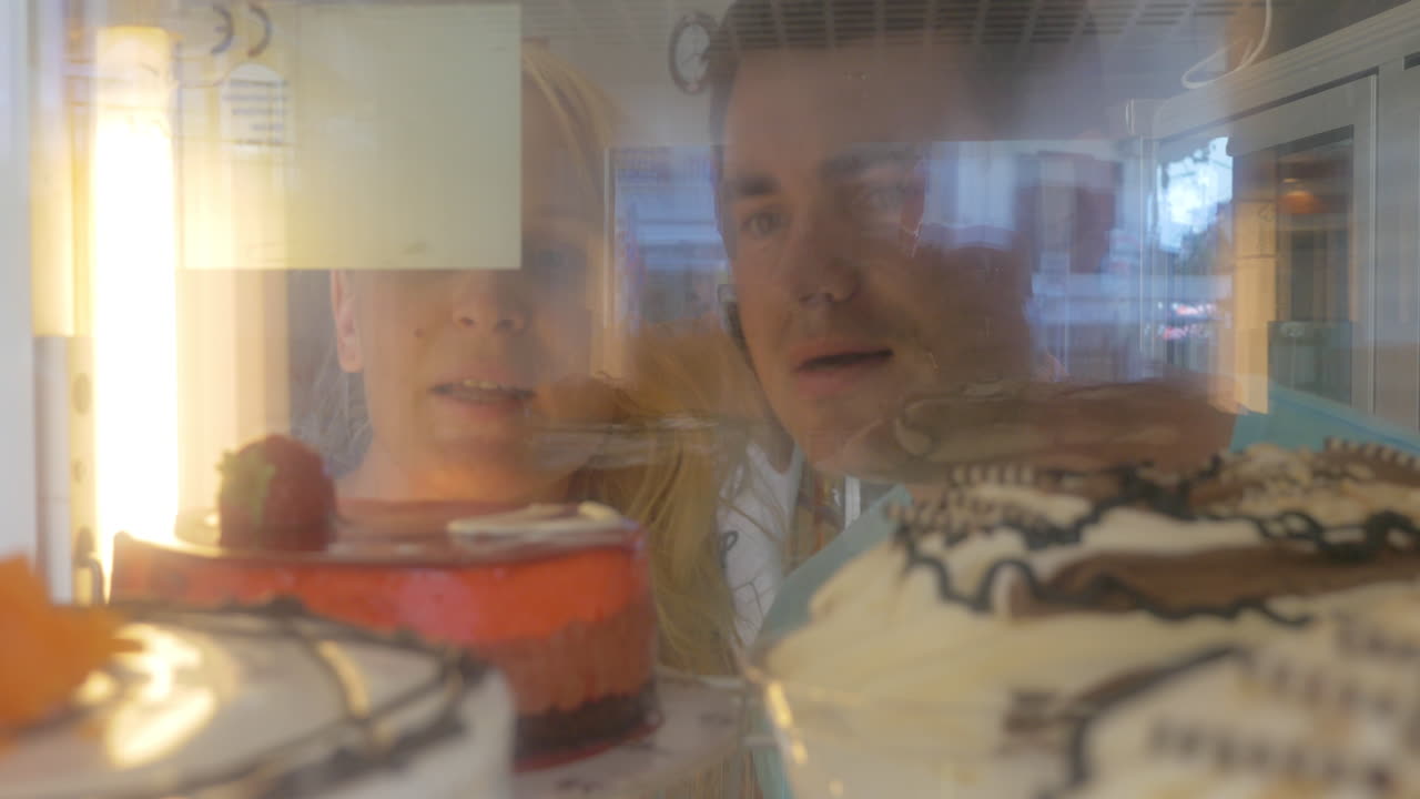 en una pastelería una pareja joven elige pastel