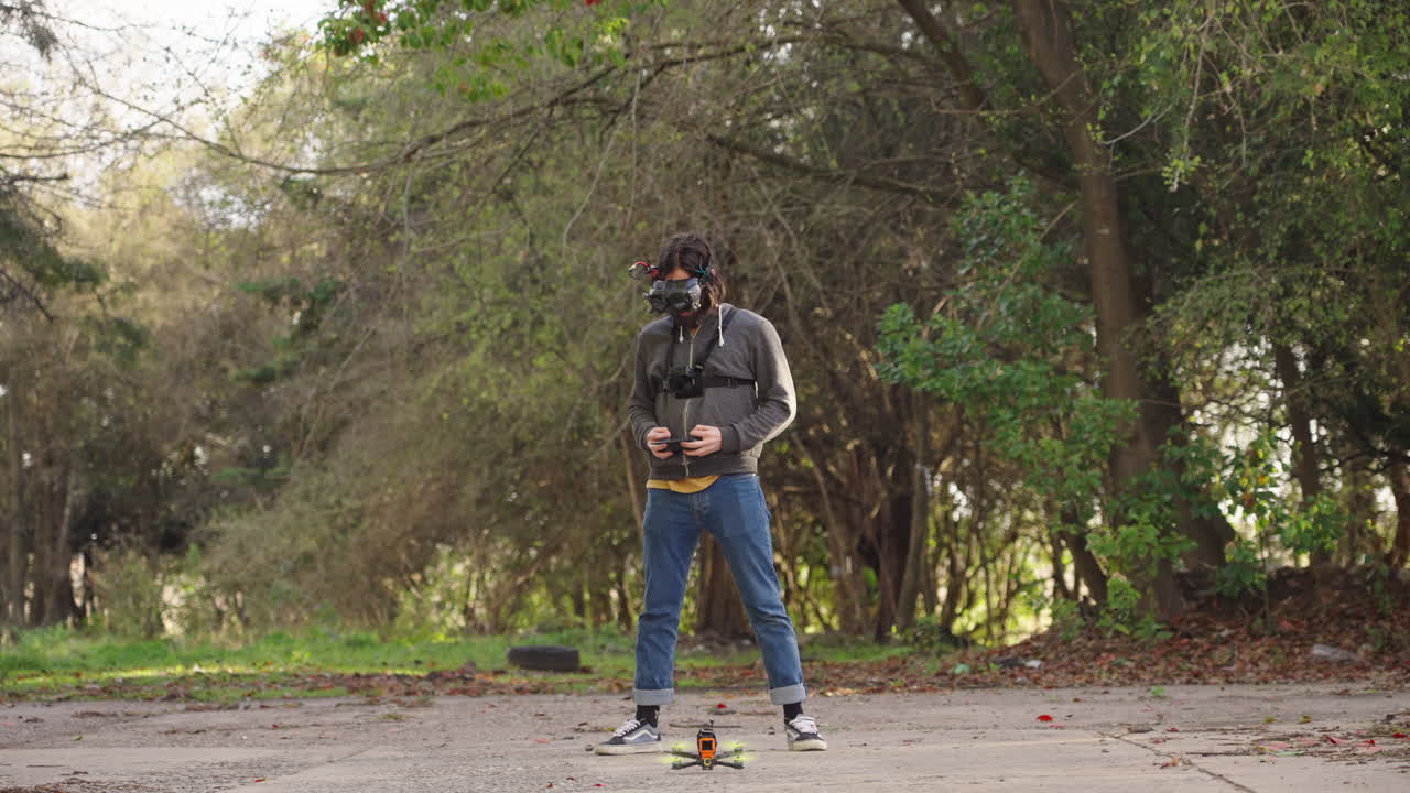 Uomo con occhiali FPV che pilota un drone con telecomando.