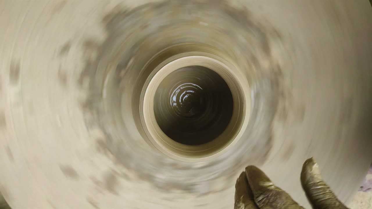 Potter making clay vessel with hands with the help of sticks.