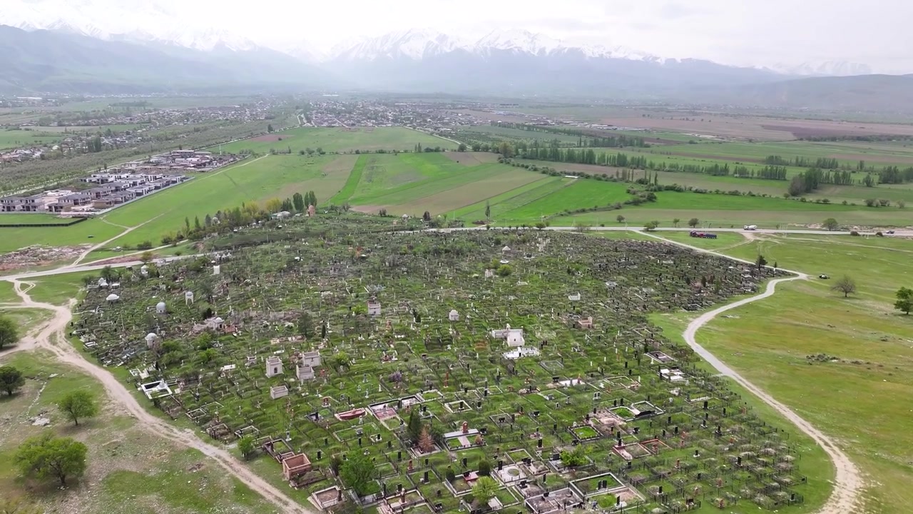 Cimitero tradizionale del Kirghizistan a Bishkek Sud e sfondo montuoso. Panorama con drone.