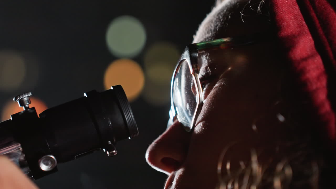 Ein weisshaariger Wissenschaftler blickt durch ein Okular, wobei sich die Brille vor dem Bokeh der Stadt spiegelt. Ein Detailaufnahme des Profils zeigt einen Bart und ruhige Hände, die die Optik ausrichten, präzise Kalibrierung und Astrofotografie-Atmosphäre.
