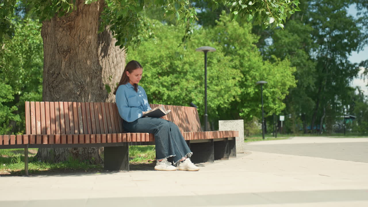 차분하게 마음챙김 독서를 하는 모습, 고요하게 야외에서 명상하는 여성, 그늘진 공원 벤치에서 평화롭게 마음챙김을 실천하는 여성, 부드러운 여름 햇살 아래 차분하게 호흡에 집중하는 여성