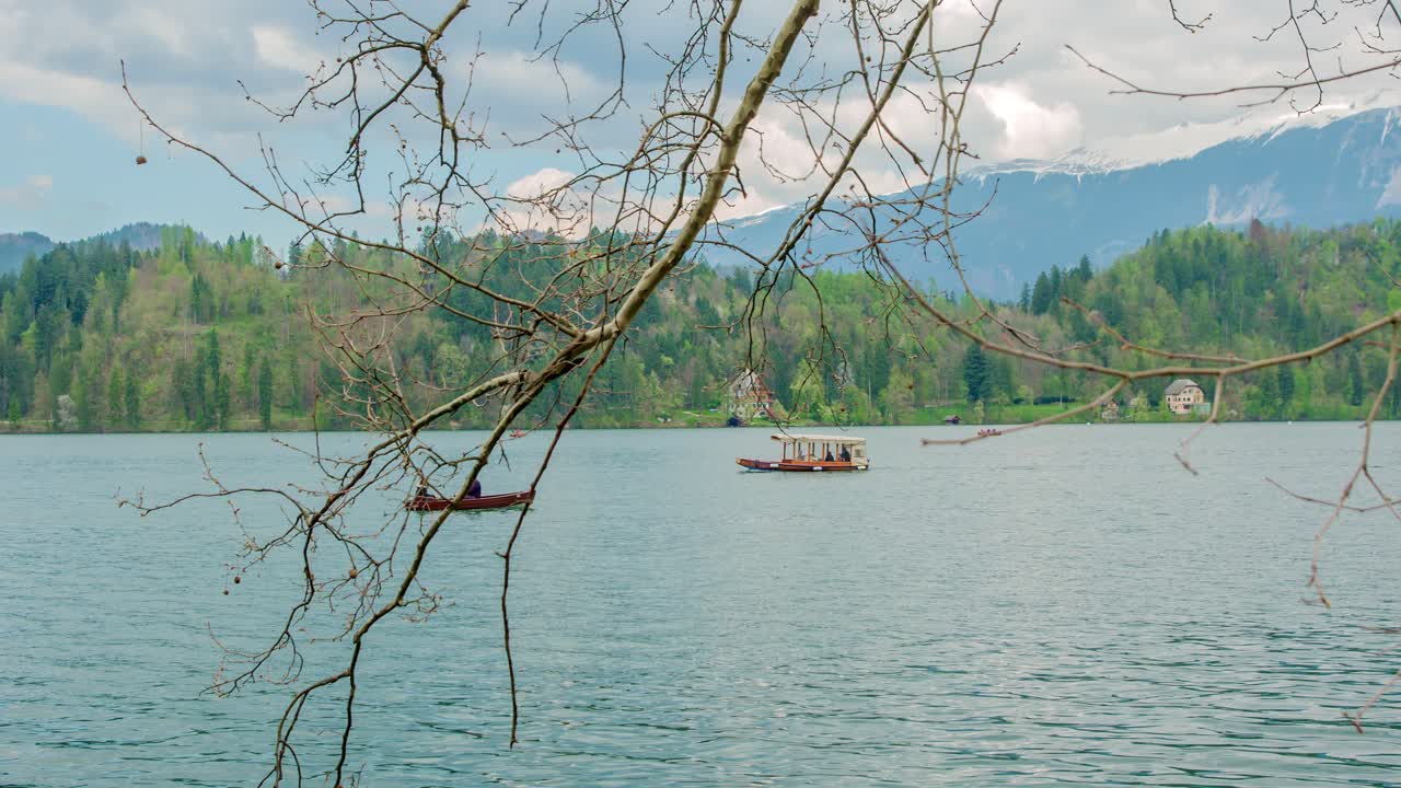 Una vista pittoresca di turisti che si godono un giro in barca nel lago calmo e bellissimo, tra splendide montagne a Bled, Slovenia