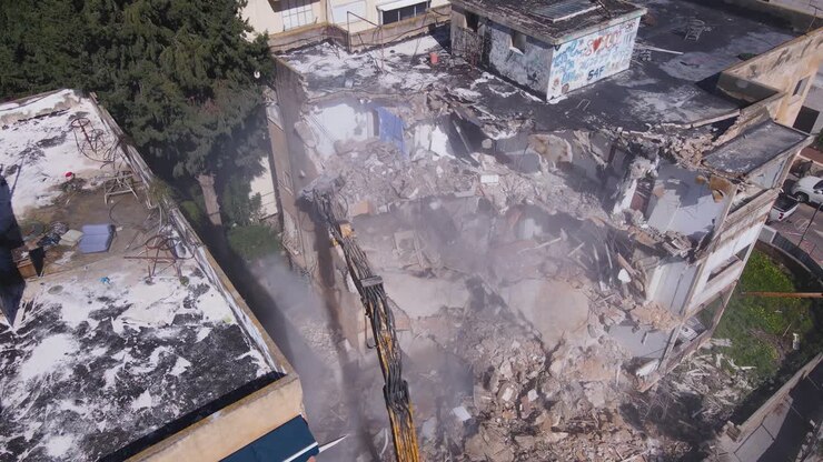 Una enorme maquinaria pesada con grúa de demolición en una ciudad con edificios antiguos.