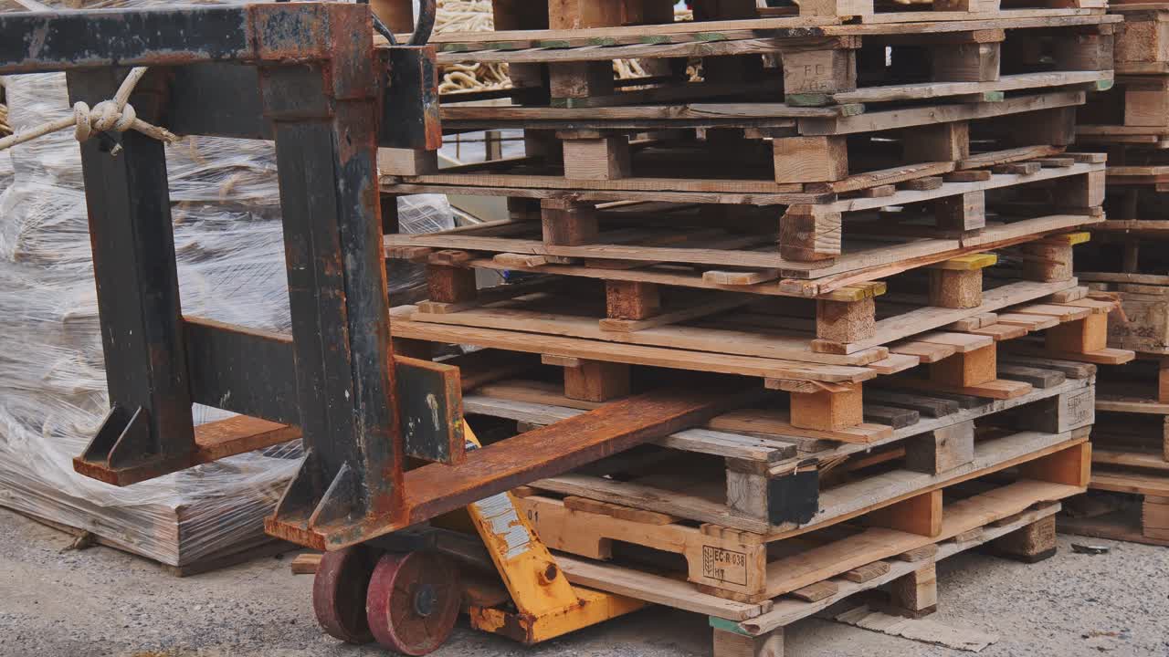 Hand pallet truck forks under wooden stack of euro transport pallets