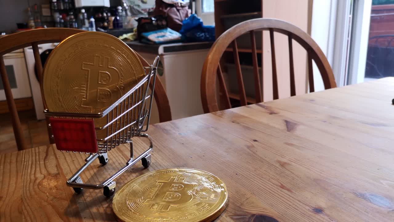 Golden bitcoin crypto currency coins in tiny shopping trolley on kitchen table concept slow push in