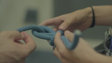 rock climber wearing safety harness learning how to make a eight rope knot