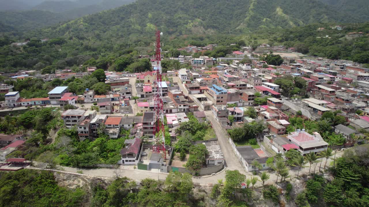 Aerial view zooming in and tilting down over a residential area in La Sabana, showcasing small buildings and houses, nestled in a mountainous region