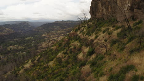 drone view flying along the edge of the canyon below towering cliffs at the butte creek canyon lookout in california.