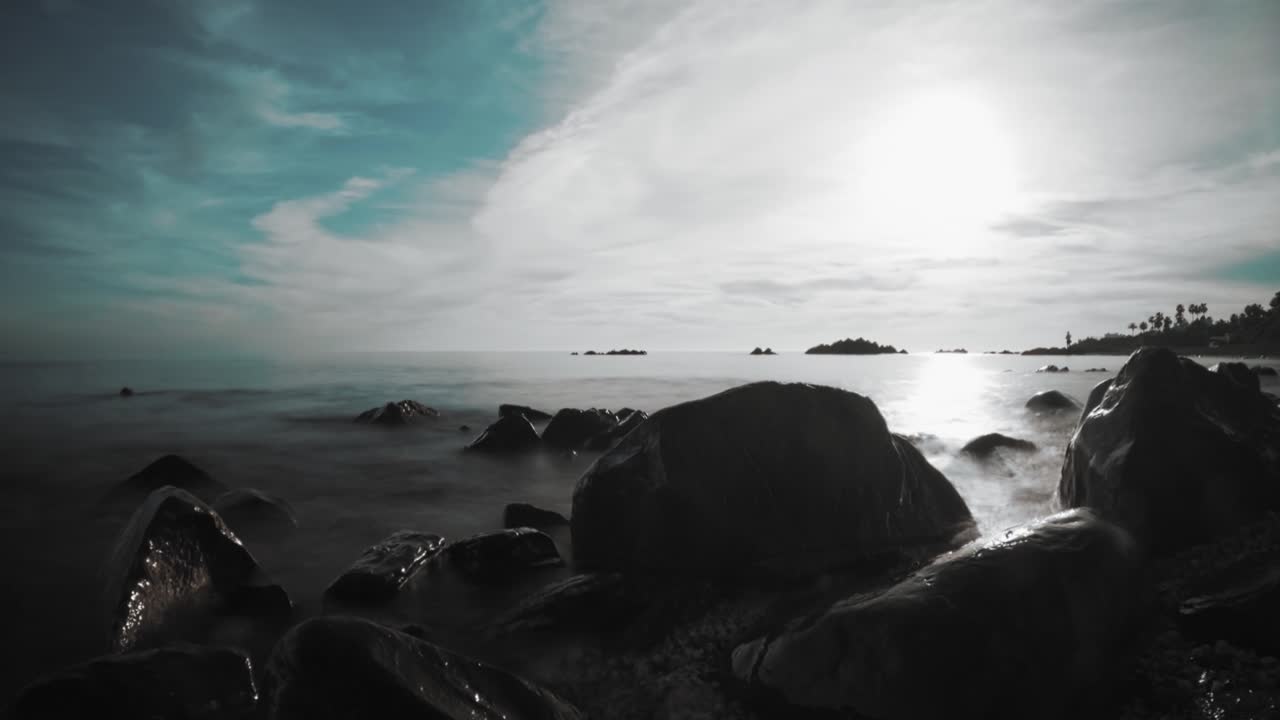 Sunset at a rocky beach with clouds and waves, long exposure