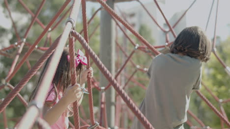 handheld shot of sister and brother climbing rope attraction