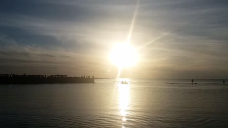 Fishing-boat-at-sea,-sunset-rays-and-wooden-pier