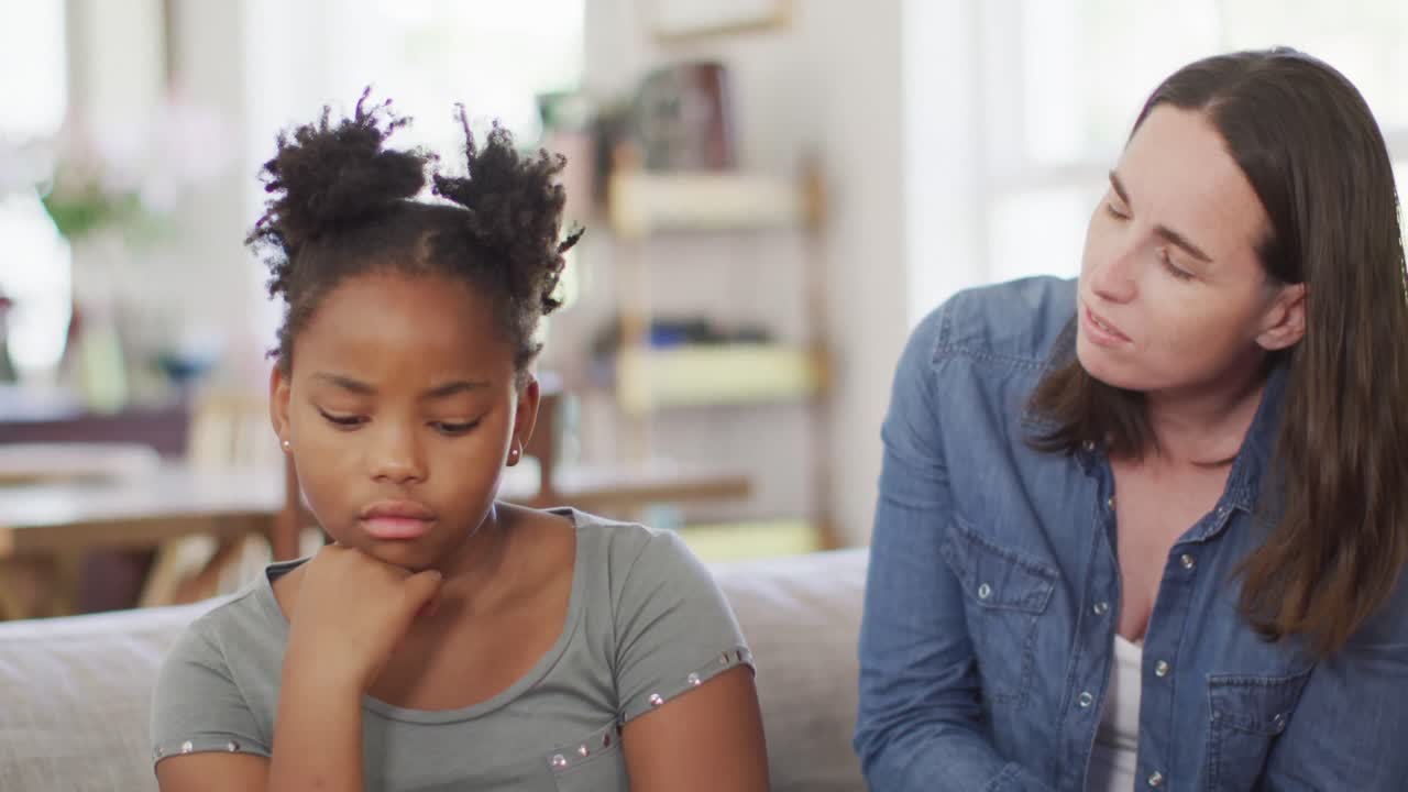Caucasian woman arguing with her african american daughter in living room