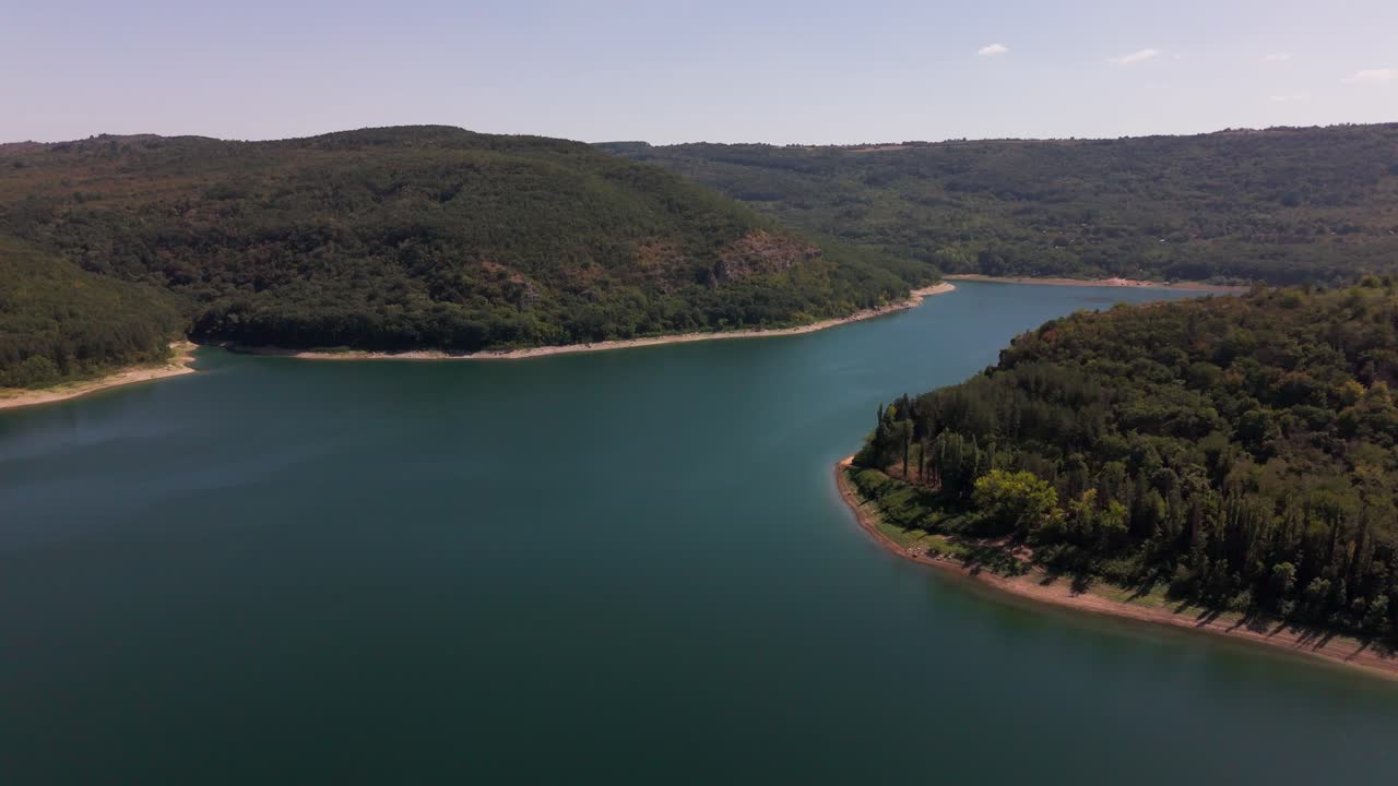 Drone pushes over Stamboliyski Reservoir, revealing the water body and lush surrounding greenery in a smooth aerial movement