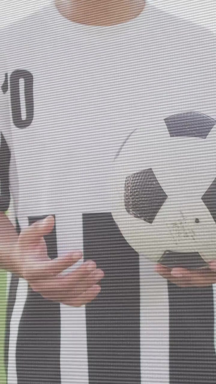 Video verticale: Uomo che aggiusta la presa dopo uno spostamento a sinistra, facendo ruotare una palla sportiva sull'erba e preparandosi a un passaggio.