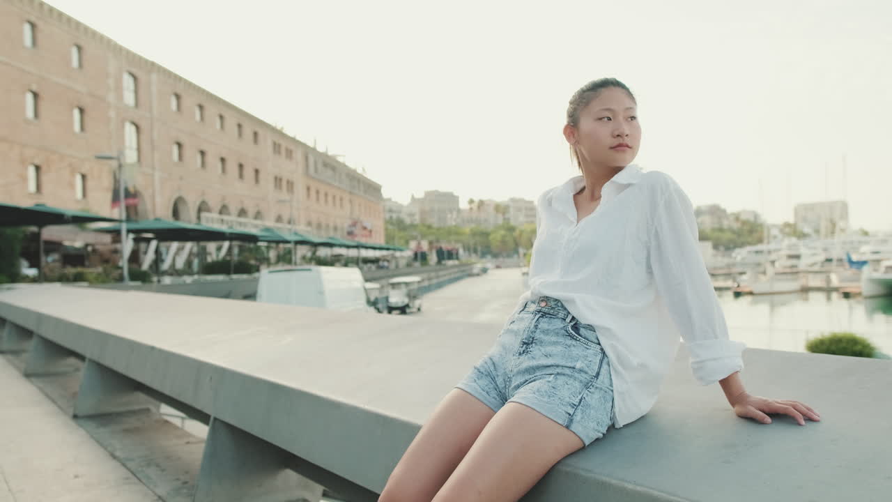 都会のマリーナで桟橋に座っている若い女性