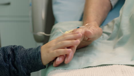 little boy holding grandmothers hand granny lying in hospital bed child showing affection at bedside for grandparent recovering from illness health care family support