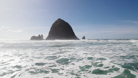 Water-rushes-past-as-the-shadow-of-Haystack-Rock-approaches-in-the-distance