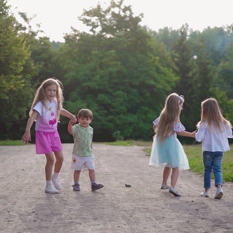 joyful children on the background of green trees in summer. girls and little boy walking merrily in the park. happy childhood.