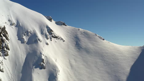 Aerial-shot-flying-towards-a-snow-covered-ridge-before-lifting-up-to-reveal-the-valley-behind-including-the-Mont-Blanc-massif-in-the-background