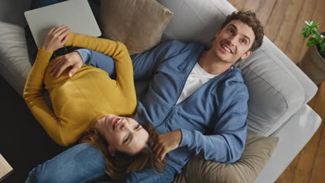 laughing sweethearts relaxing sofa at new house top view closeup. pair enjoying
