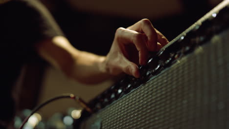 Guitarist-turning-knobs-of-amplifier-in-studio