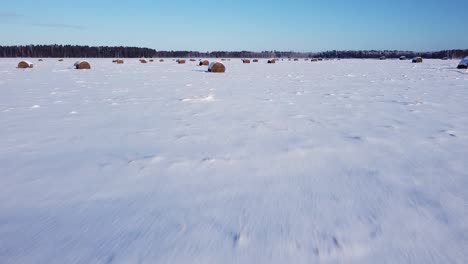 Hay-roll-filed-covered-with-snow-aerial-view-low-sunlight-long-shadows