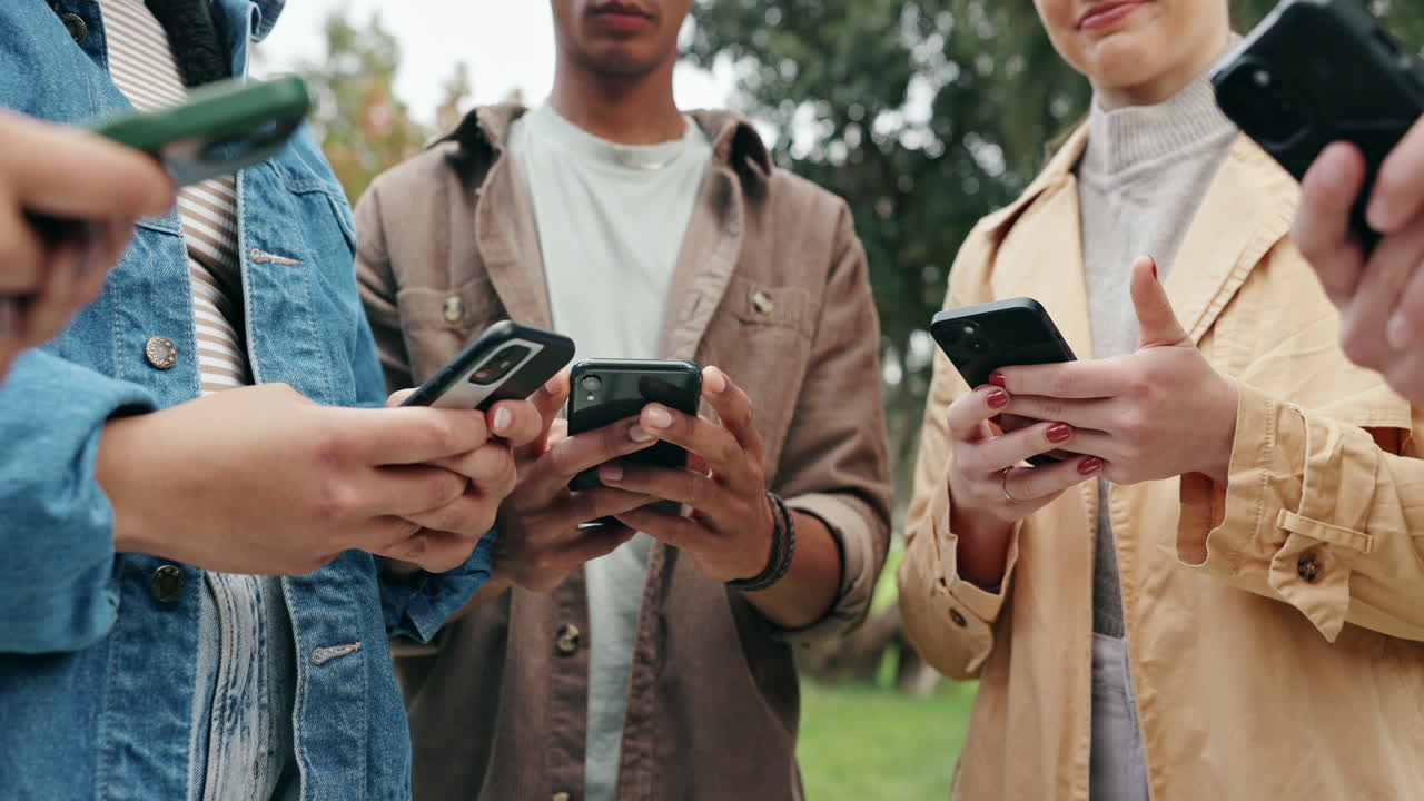Friends using smartphones in a park