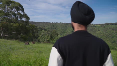 Indian Sikh Man Looking At Kangaroos In Grass Field - medium