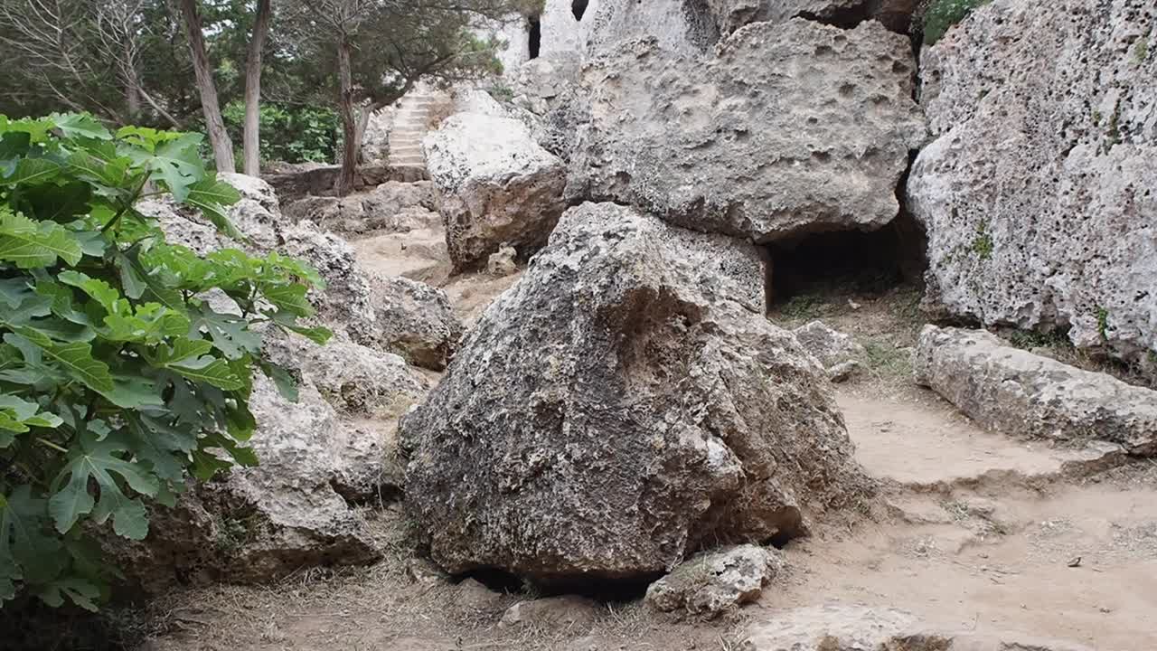 Rock formations and a narrow path in the ancient Necropolis Cala Morell, Menorca