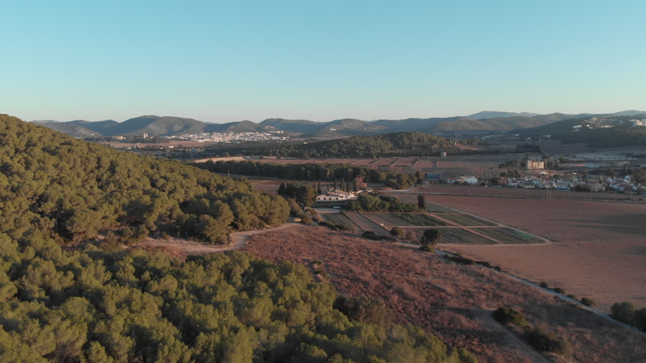 Tomada de drone de terras agrícolas onde a floresta da montanha começa e vista panorâmica de cidade distante, terras agrícolas e montanhas que se estendem infinitamente