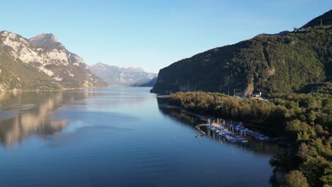 a beautiful view overlooking walensee lake with gentle ripples in the dark blue water, a small marina, and majestic mountain scenery on the bright horizon