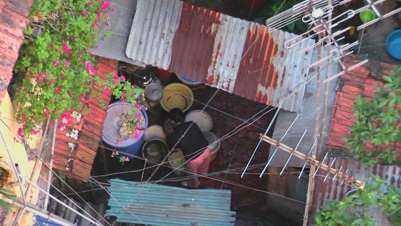 작은 베트남 동네를 드러내기 위해 옥상에서 일하는 여성에게서 물러나다