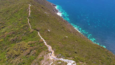 4K-drone-video-flying-over-two-people-hiking-the-Bald-Head-Walking-Trail-within-the-Torndirrup-National-Park-in-Albany,-Western-Australia