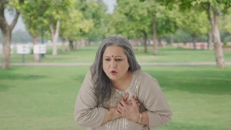 sick indian old woman having a heart attack in park