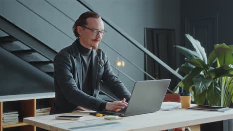 focused businessman working on laptop at desk in modern office