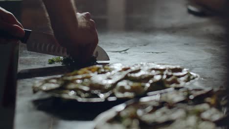 Pizza-maker-cutting-parsley-in-kitchen